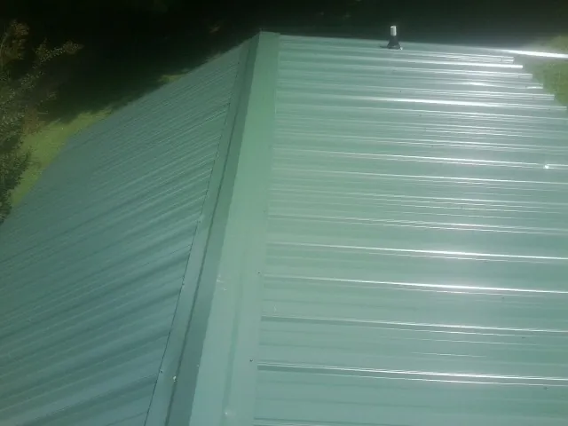 New green metal panels meeting at the ridge of a roof — Flat Roof Repair work by our crew in Doylestown