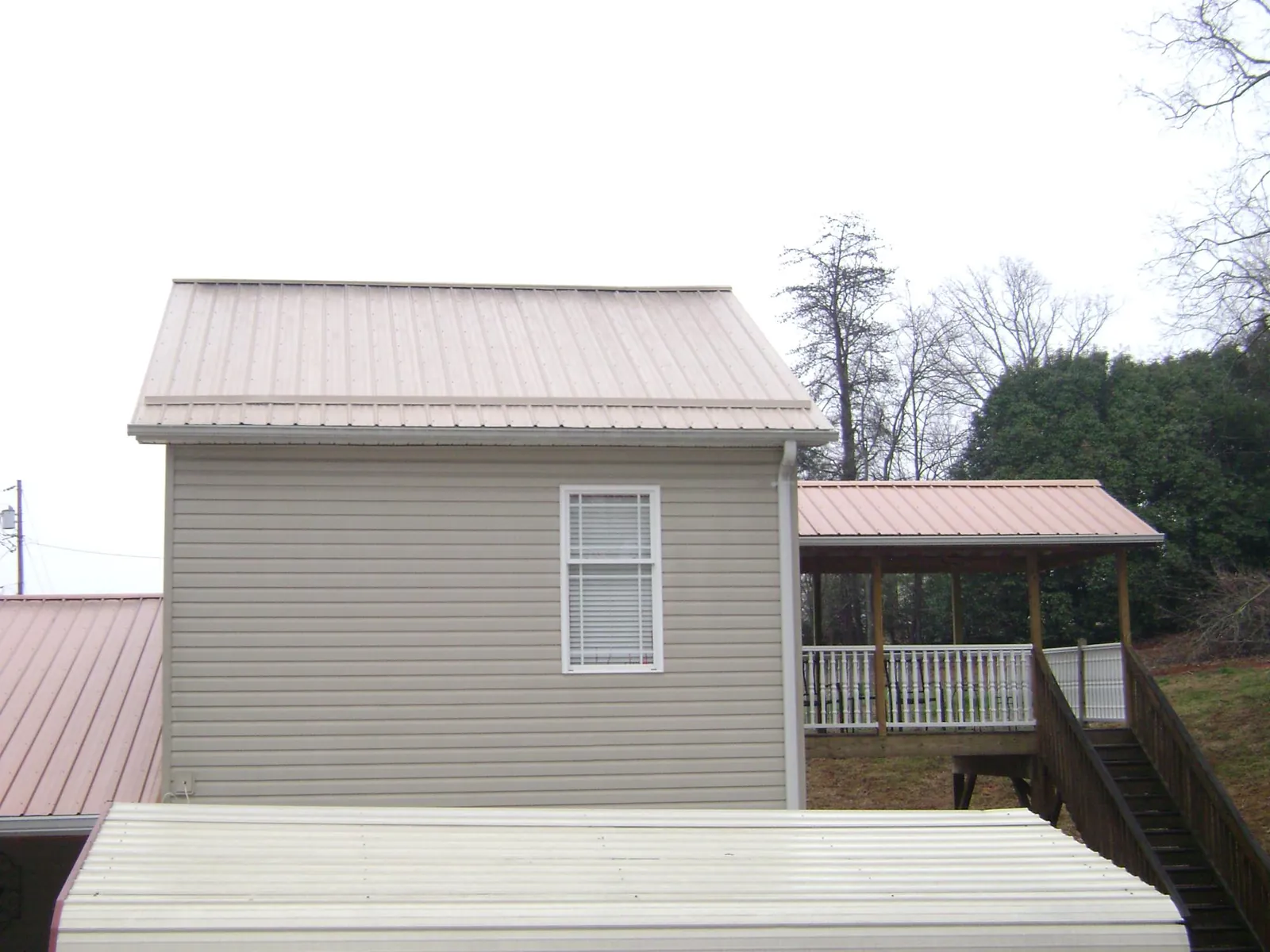 Tan metal roofs on a two story addition and attached porch, from a Roof Replacement job in Doylestown